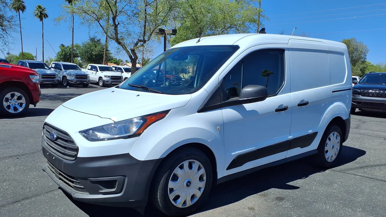 A white compact delivery van parked at the curb on a sunny day