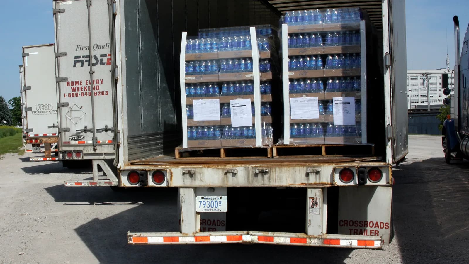 Pallets of bottled water stacked inside an open delivery trailer