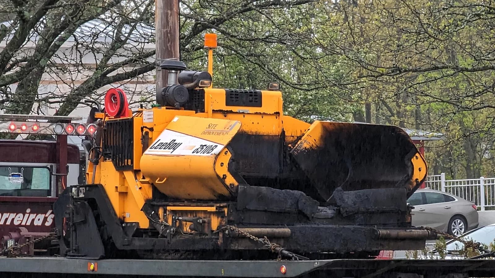 Une finisseuse d'asphalte orange posant un nouveau revêtement dans une rue résidentielle