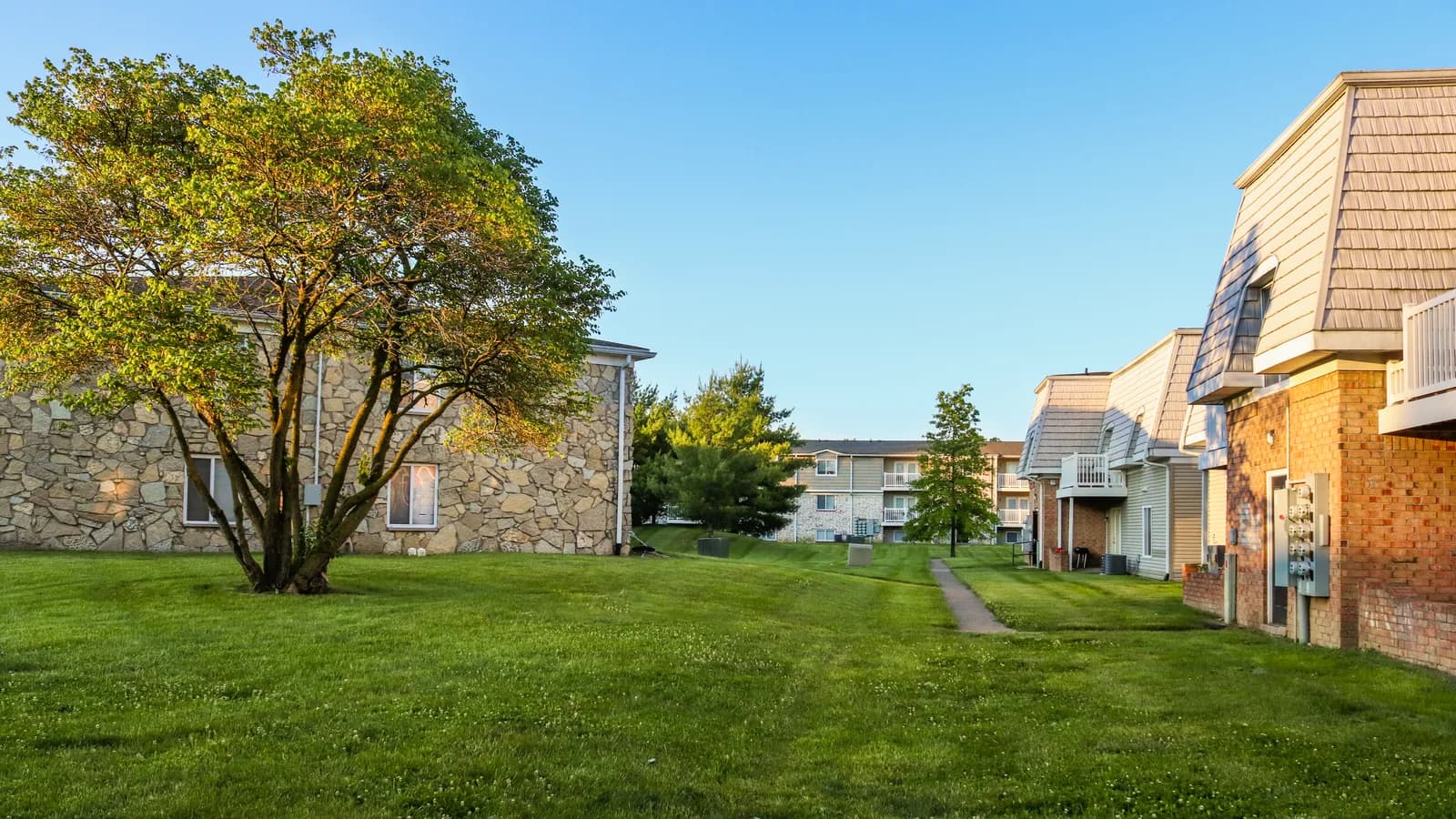 A landscaped apartment complex with lawns, mature trees and low-rise buildings