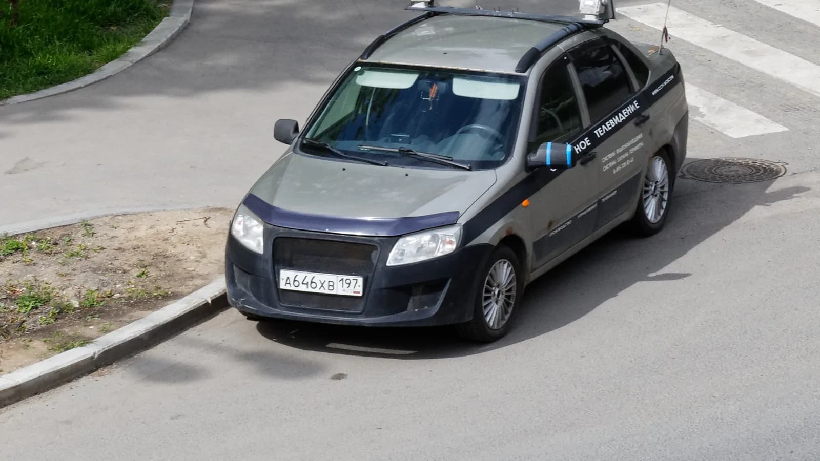 A grey patrol car with a roof light bar parked at a crossing