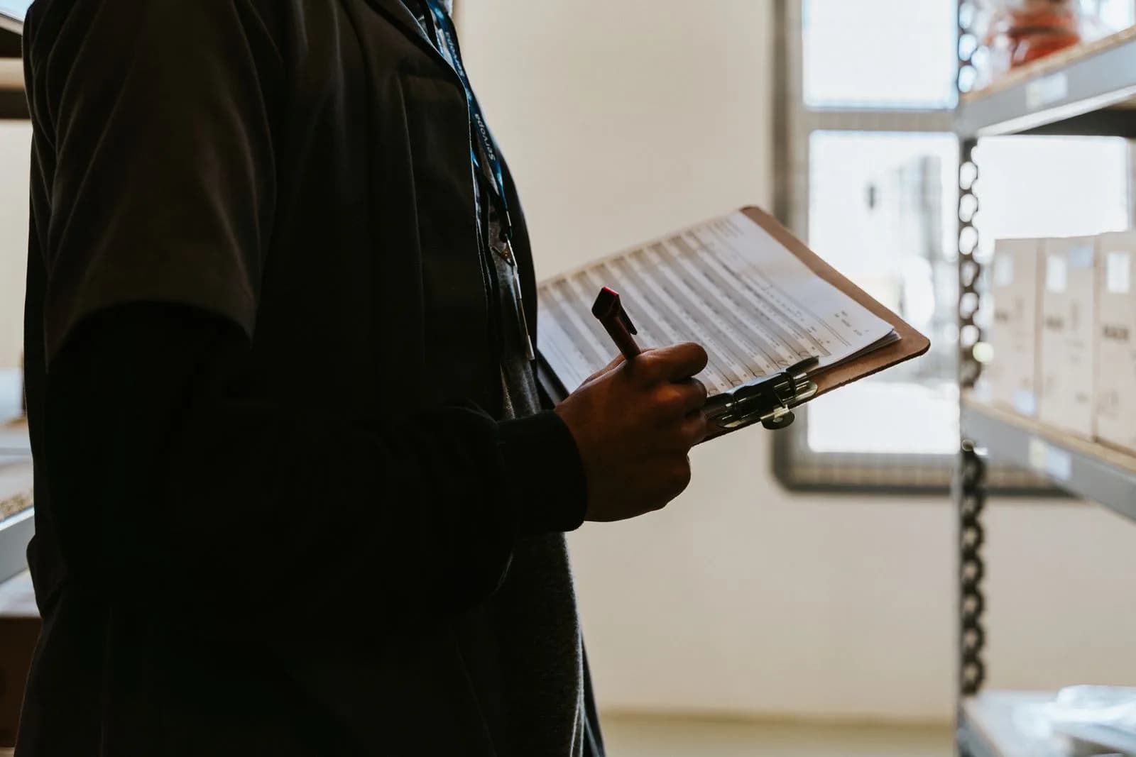 A warehouse worker holding a clipboard while reviewing inventory