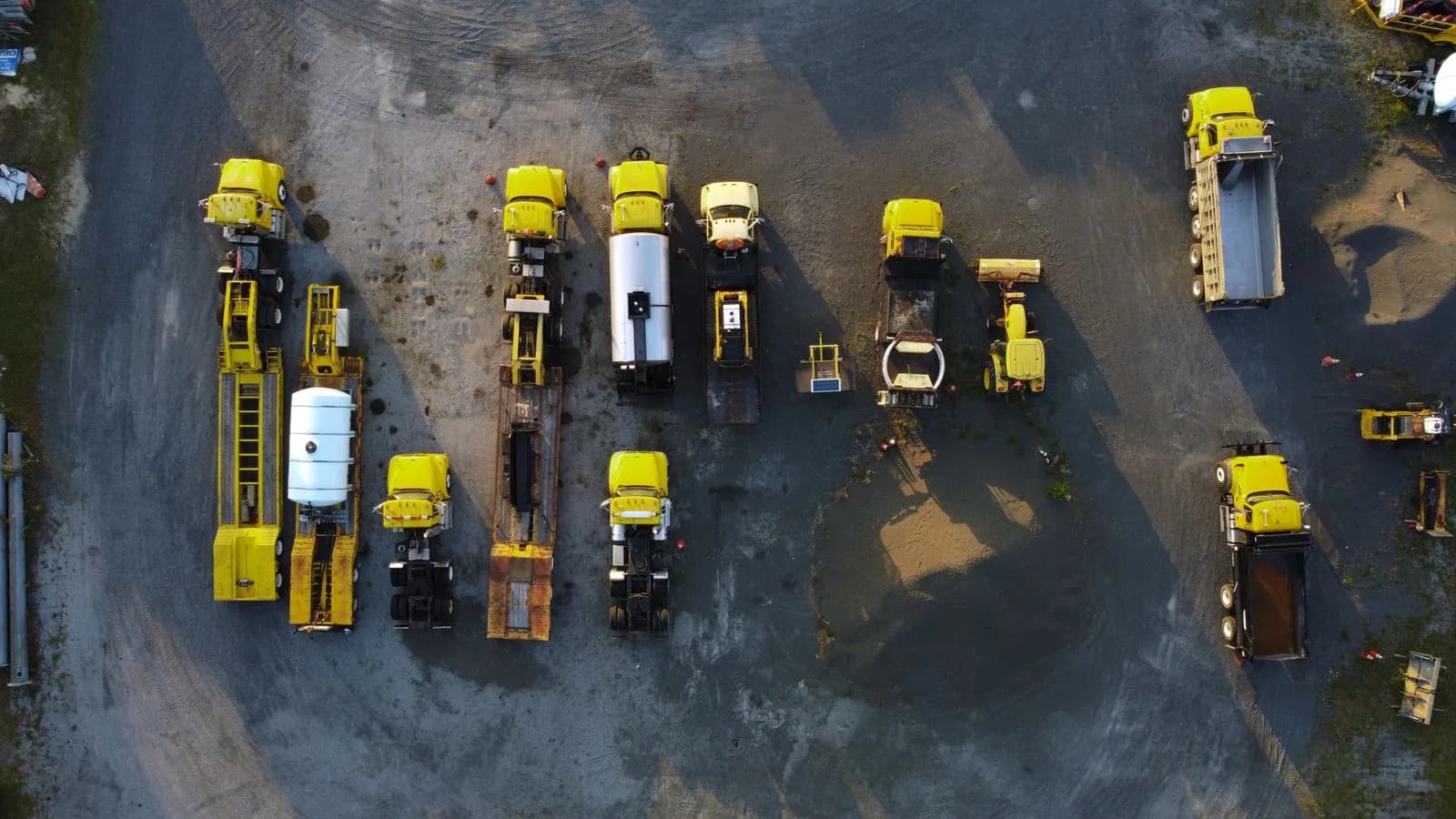 An aerial view of yellow construction trucks parked in rows
