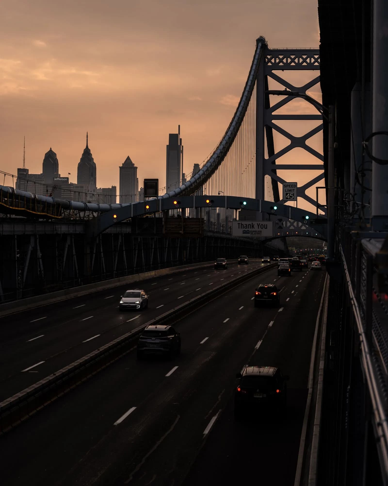 The Benjamin Franklin Bridge and highway leading into the Philadelphia skyline at sunset