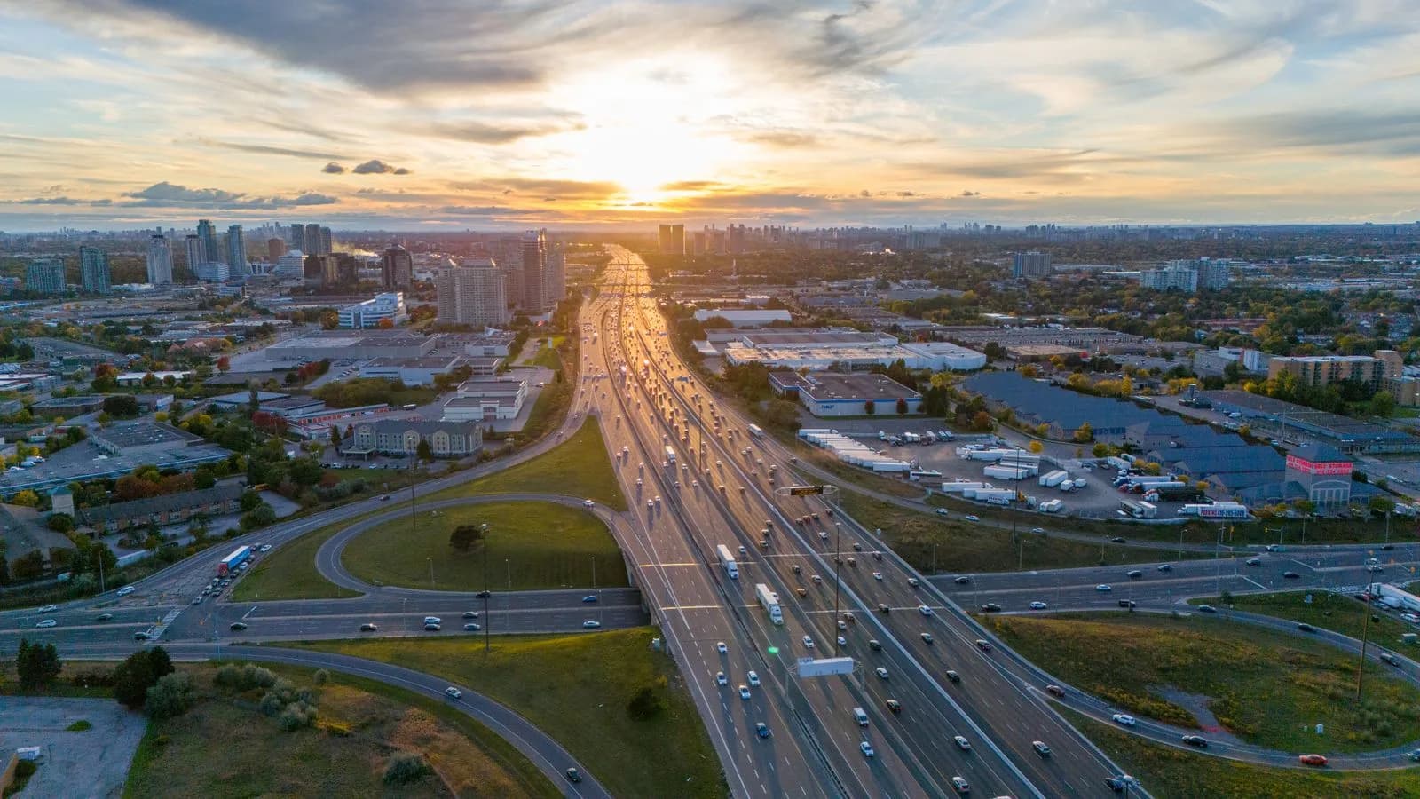 Aerial view of a busy Toronto highway at sunset with the city skyline in the background