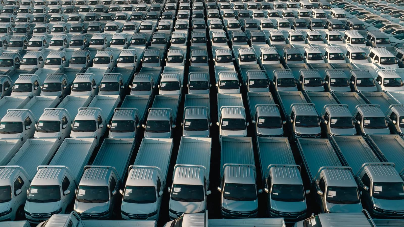 Aerial view of hundreds of new pickup trucks parked in neat rows