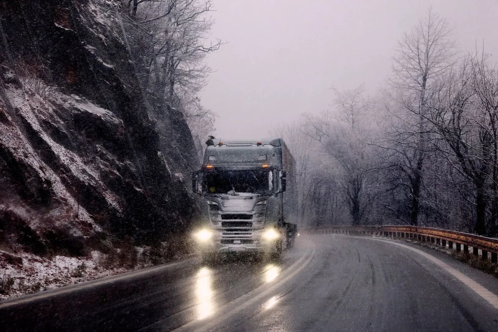 A commercial truck driving on a highway through a Canadian mountain landscape