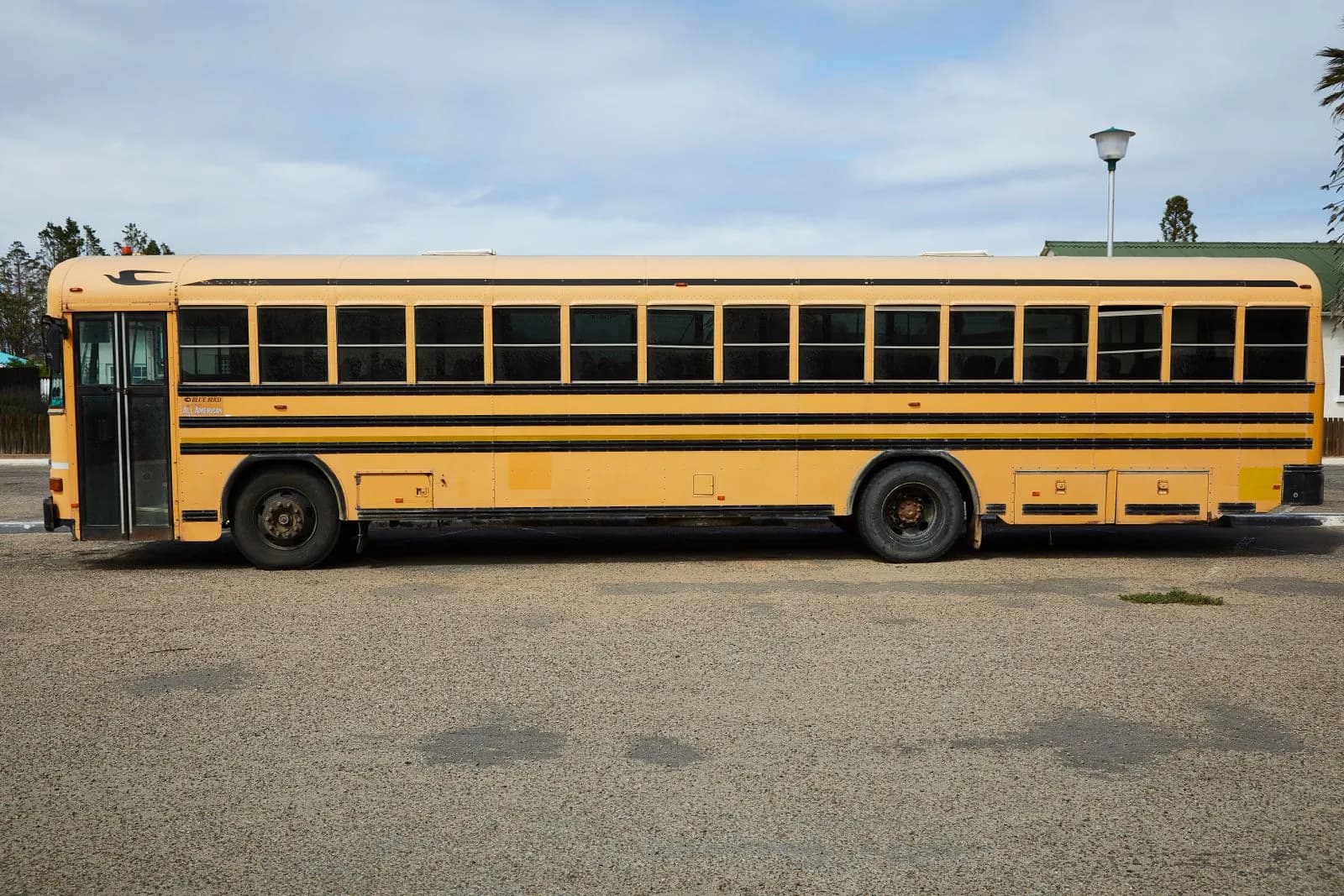 Un autobus scolaire jaune stationné dans un terrain par temps nuageux