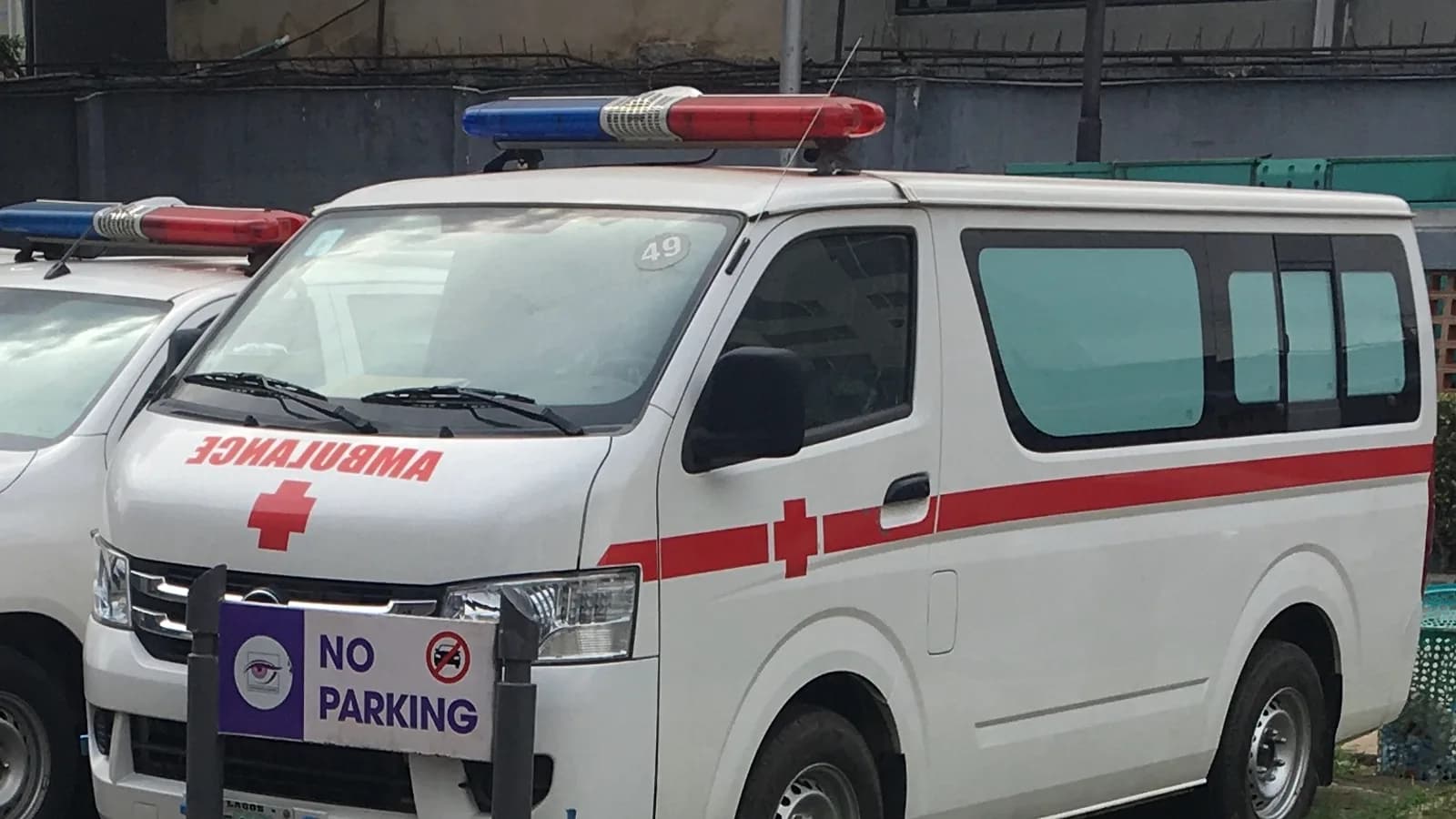 A white ambulance with red markings parked outside a building