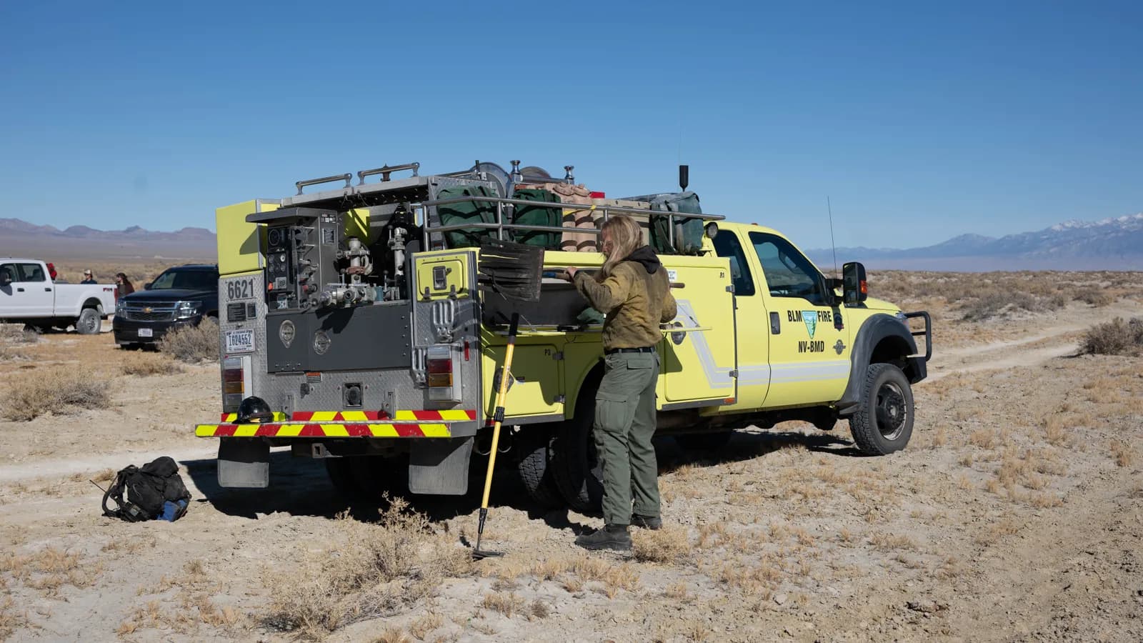 An animal control officer beside a service truck in open country