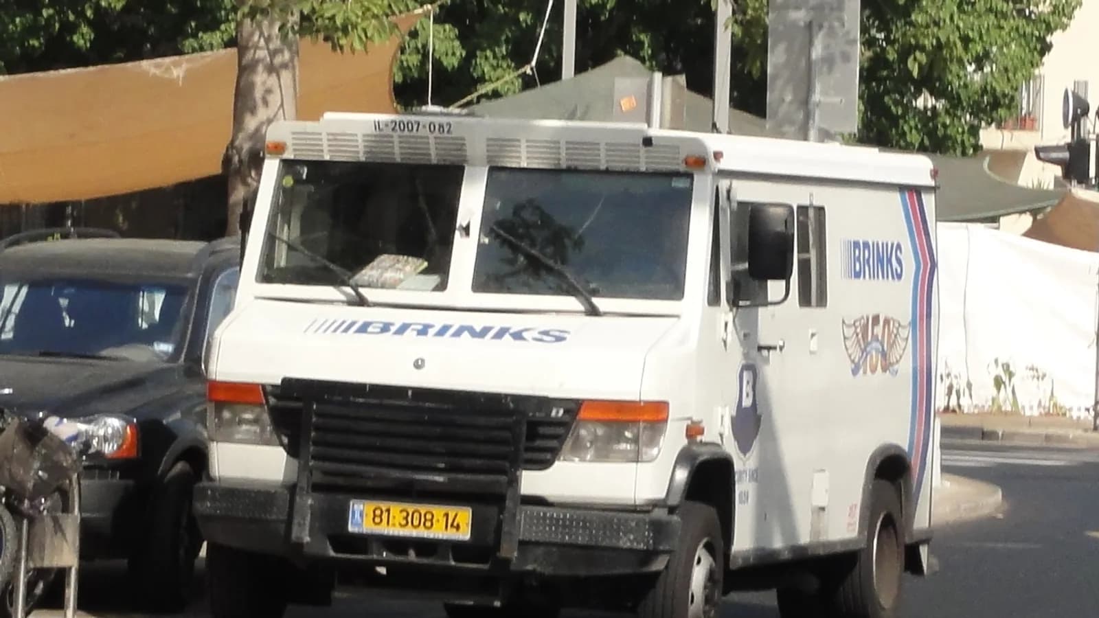 A white armored transport van parked on a city street