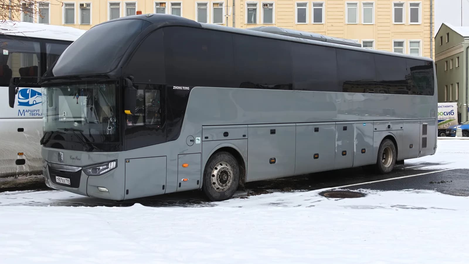 A motorcoach parked in front of a building on a winter day
