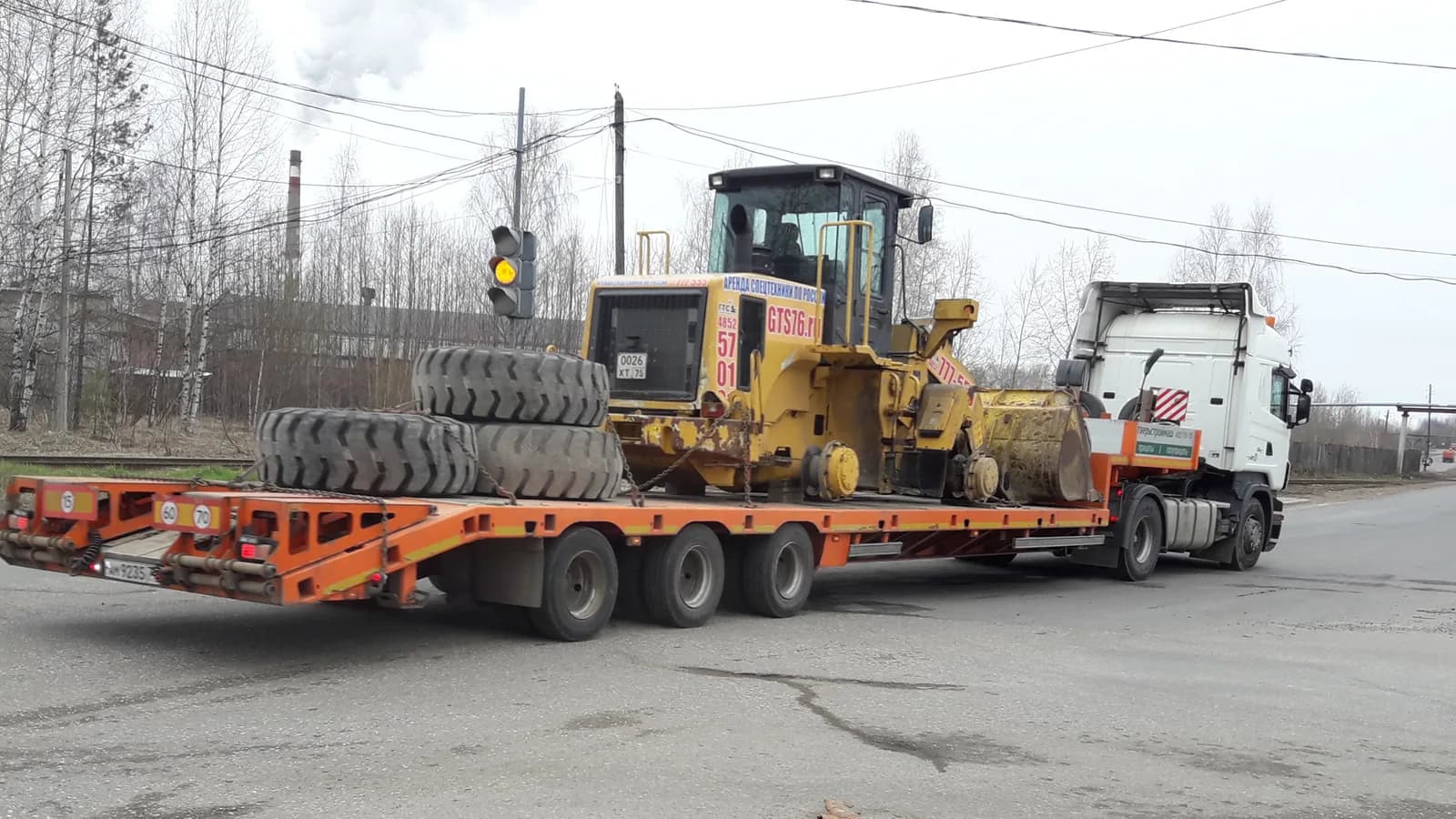 A lowboy trailer carrying a wheel loader behind a heavy truck