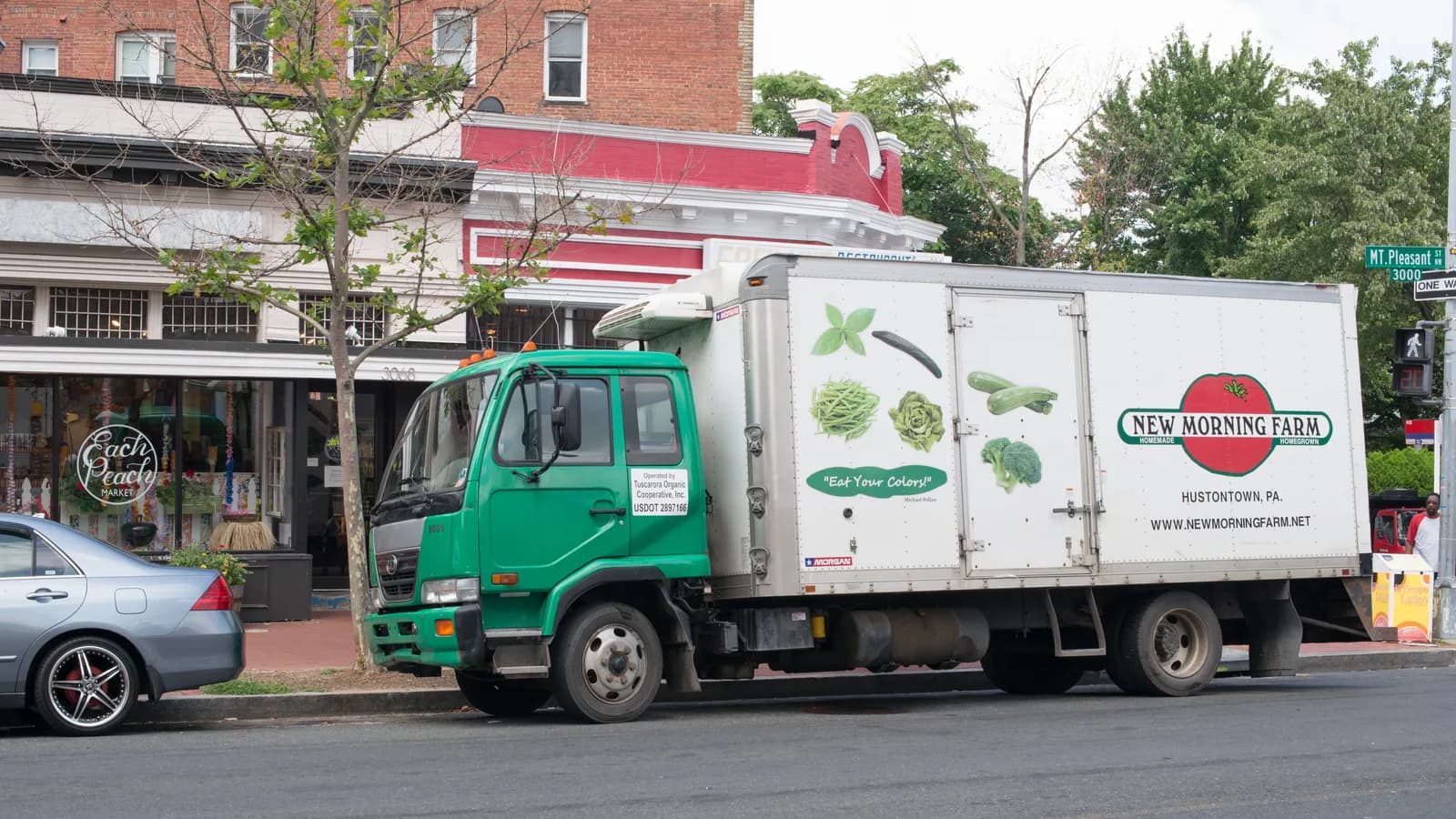 A refrigerated produce delivery truck parked outside a restaurant