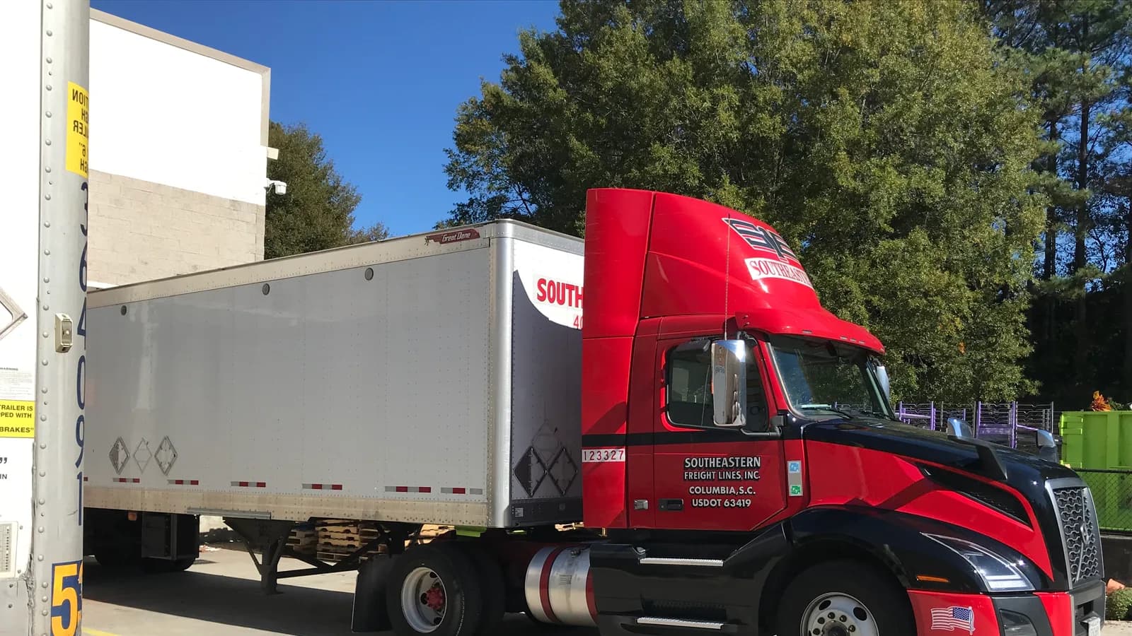 Un tracteur routier rouge avec une remorque fourgon stationné à un quai de chargement