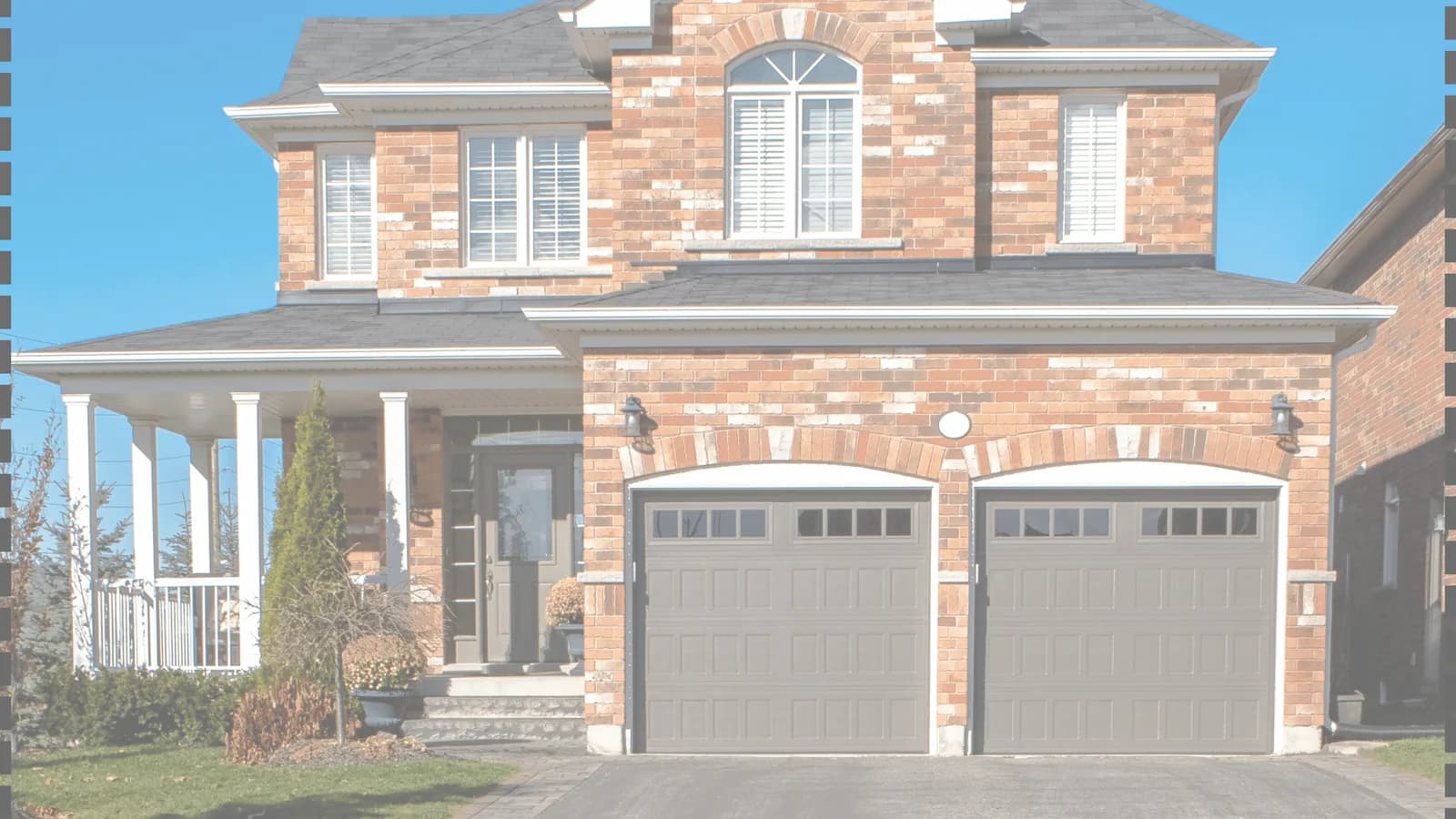 A brick house with two closed residential garage doors