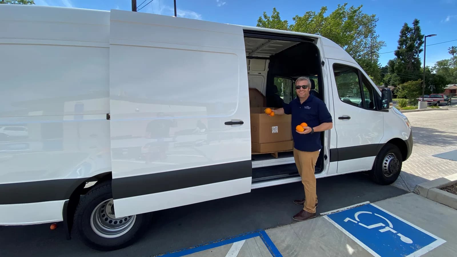 A delivery driver at the open side door of a white cargo van