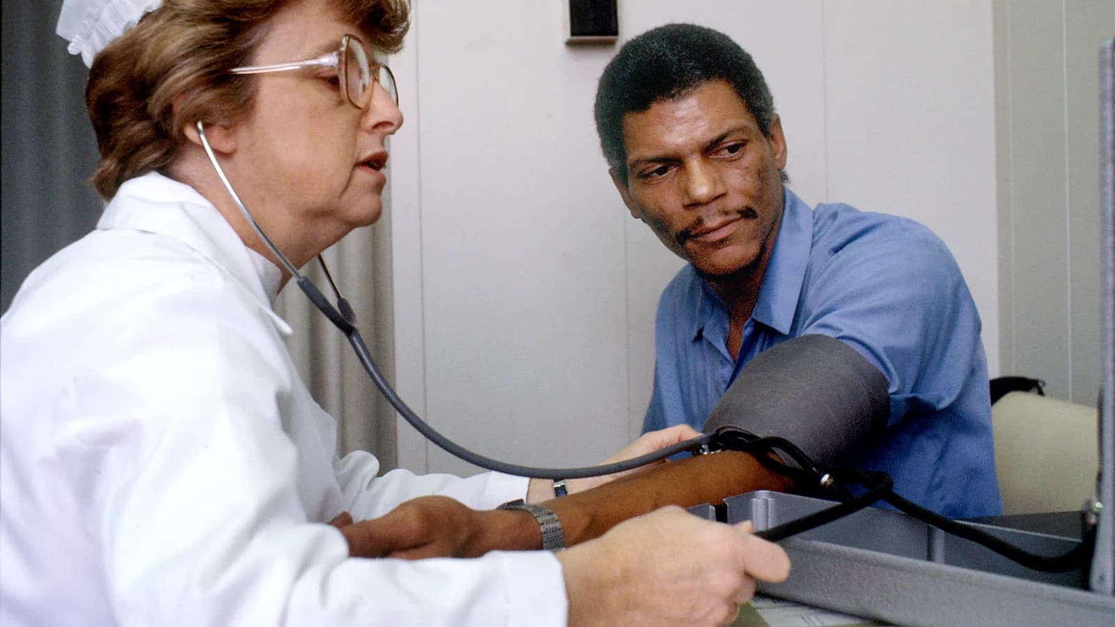 A nurse checking a seated patient's blood pressure with a cuff