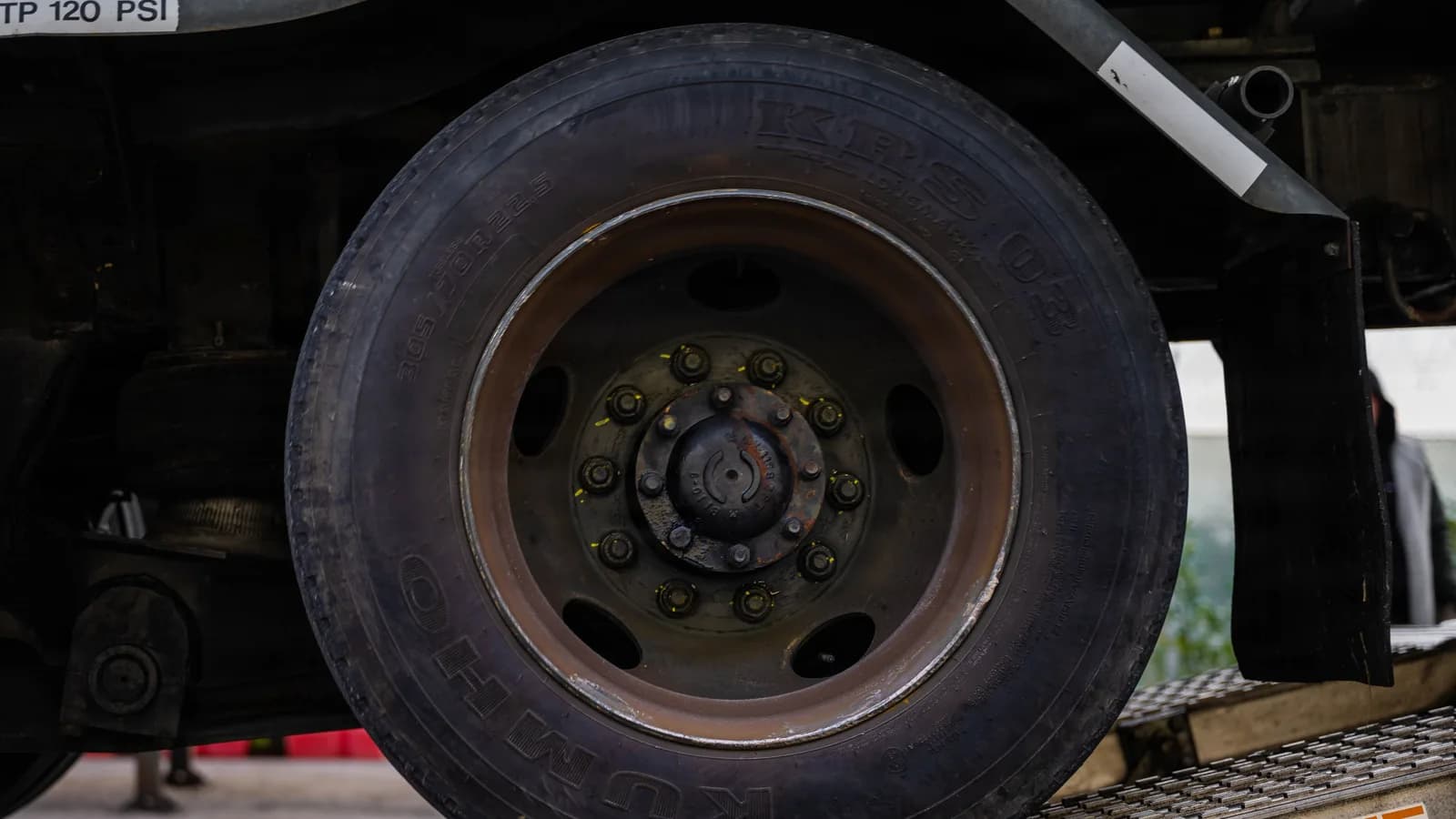 A close-up of a heavy truck wheel and tire from ground level