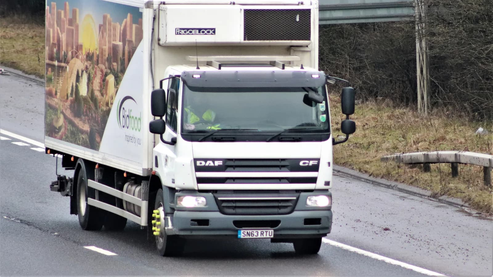 A refrigerated box truck with a roof-mounted reefer unit on a road