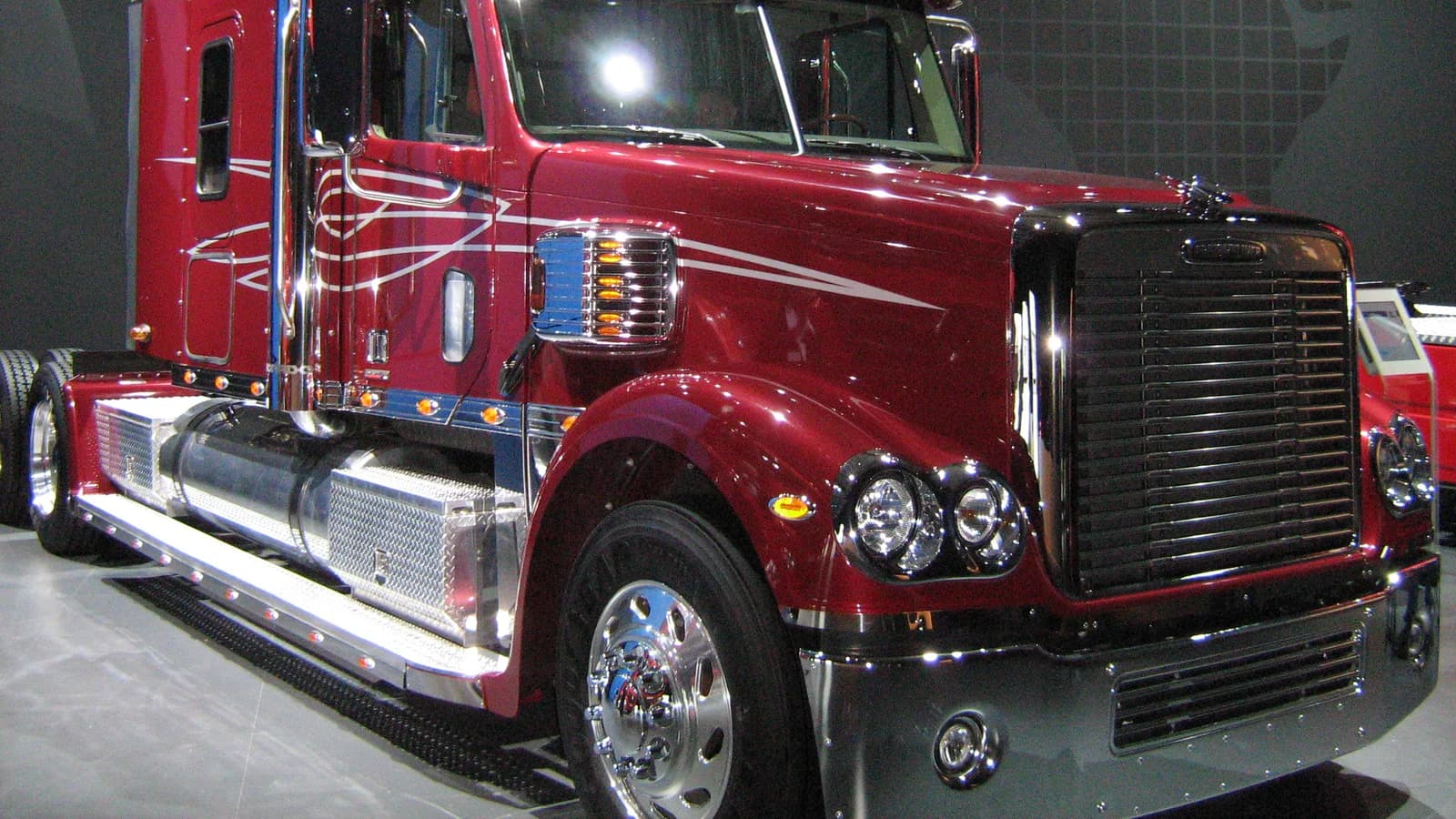 A red long-haul semi tractor parked at a truck stop
