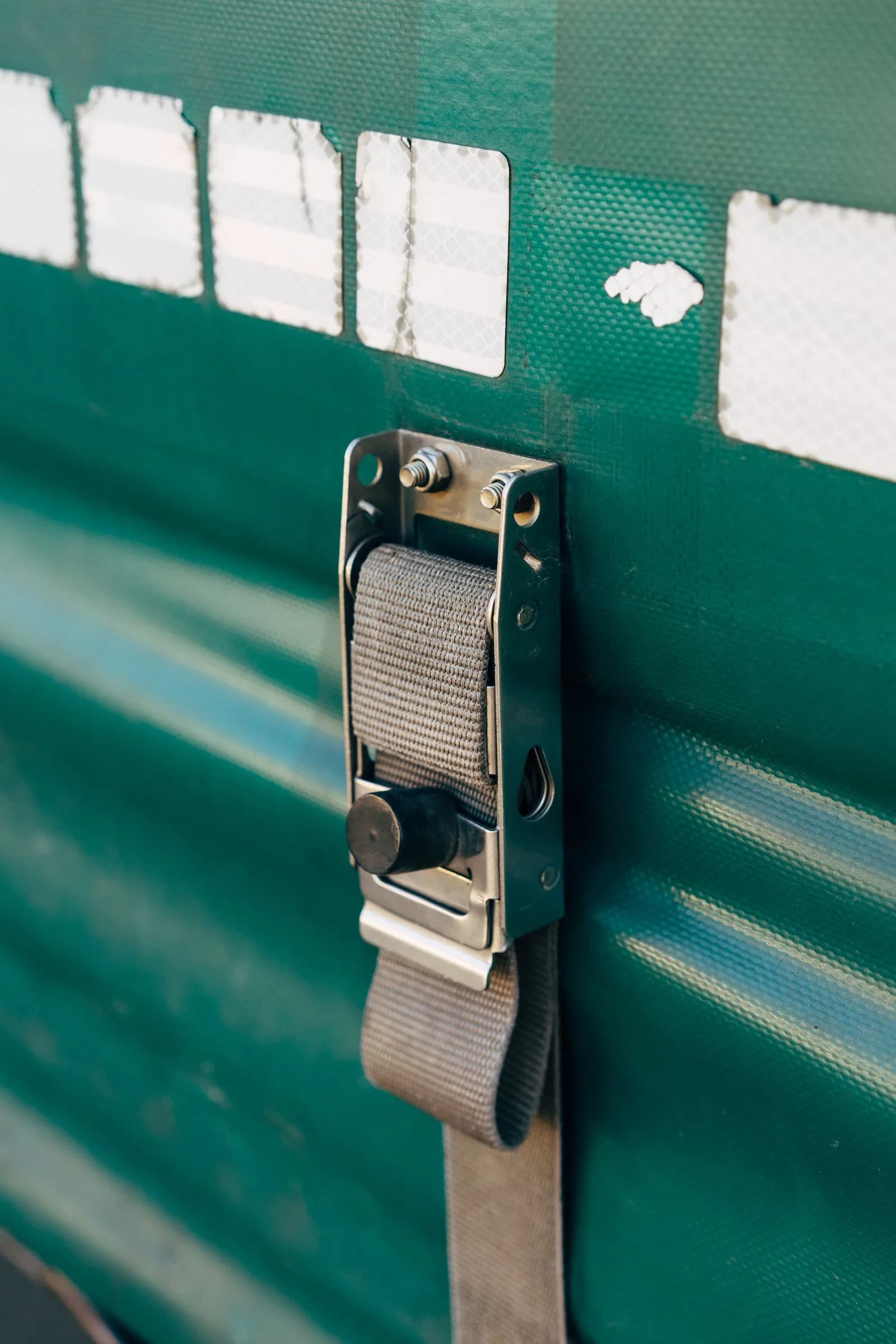 Close-up of a ratchet strap securing a tarp on a commercial trailer