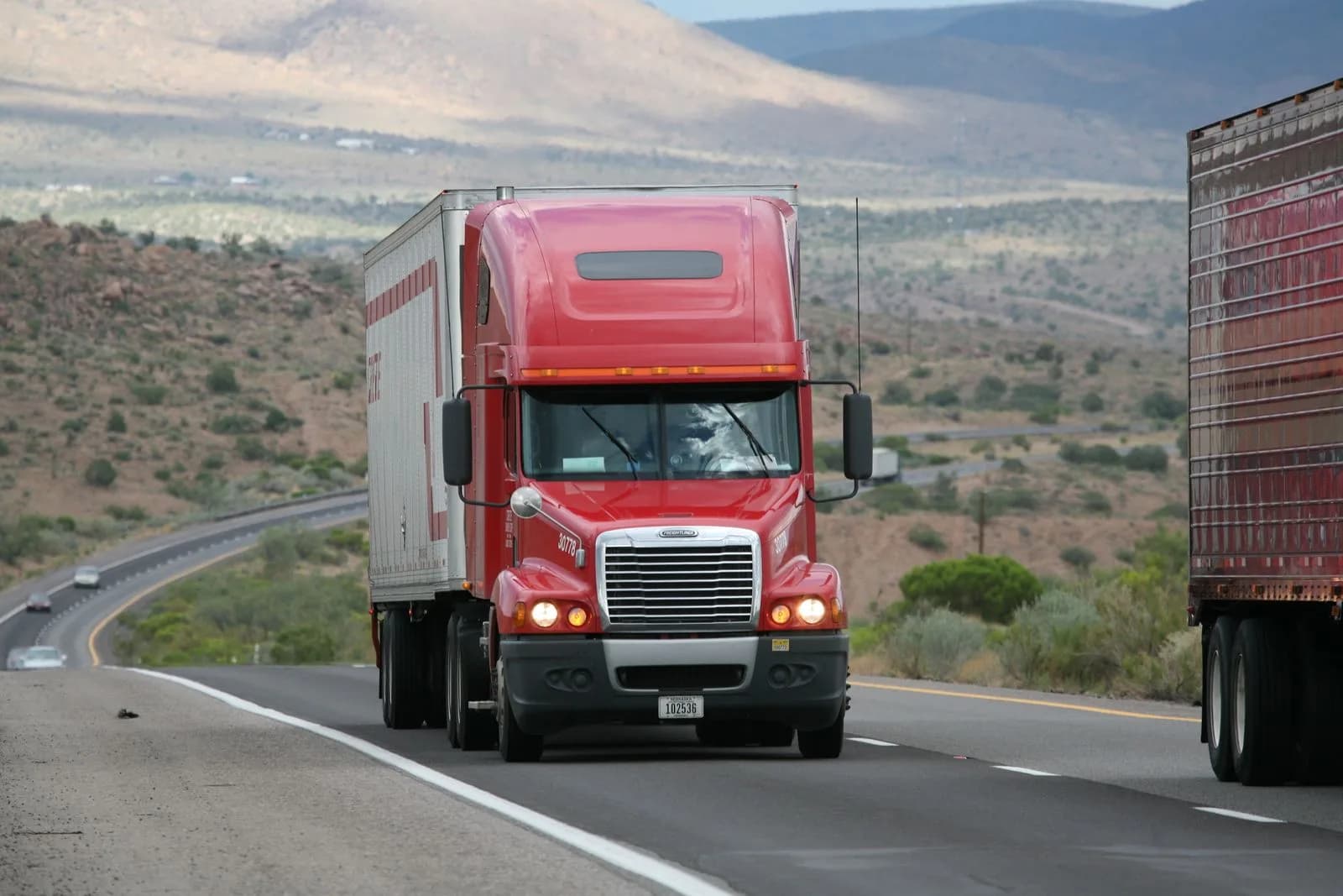 A semi-truck driving on a highway through a mountainous landscape
