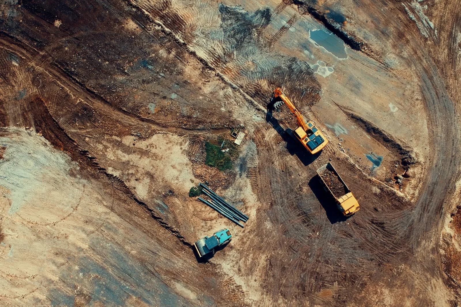An aerial view of a construction site with an excavator and dump truck