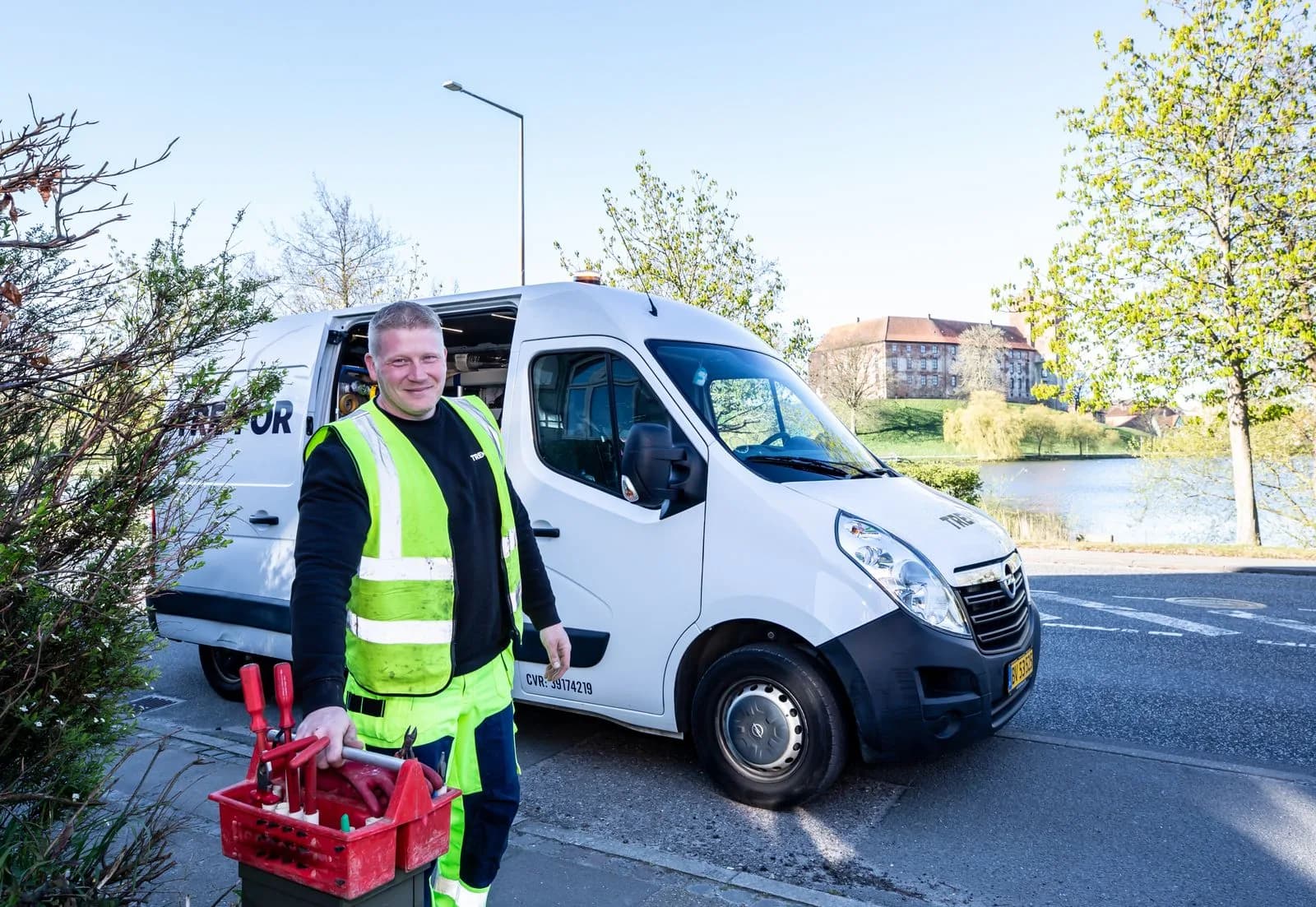 A field service technician holding a tool crate beside a work van