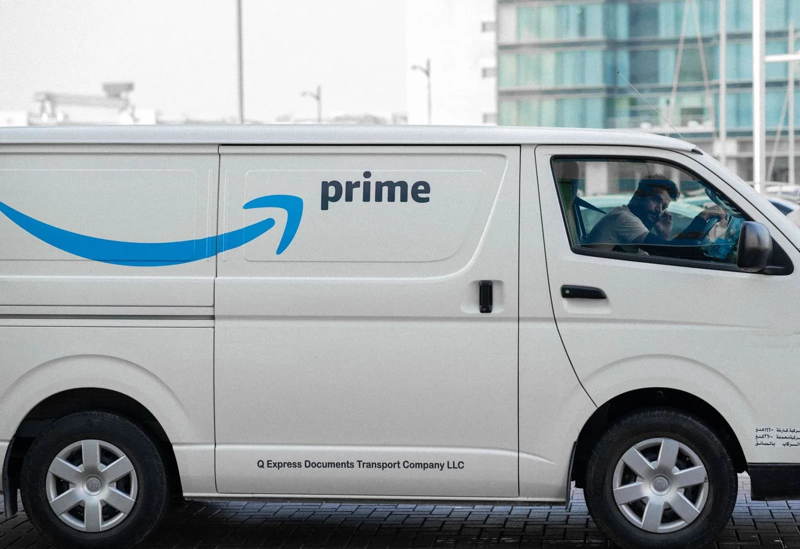 A courier in a branded delivery van handing a parcel to a customer on a busy city street