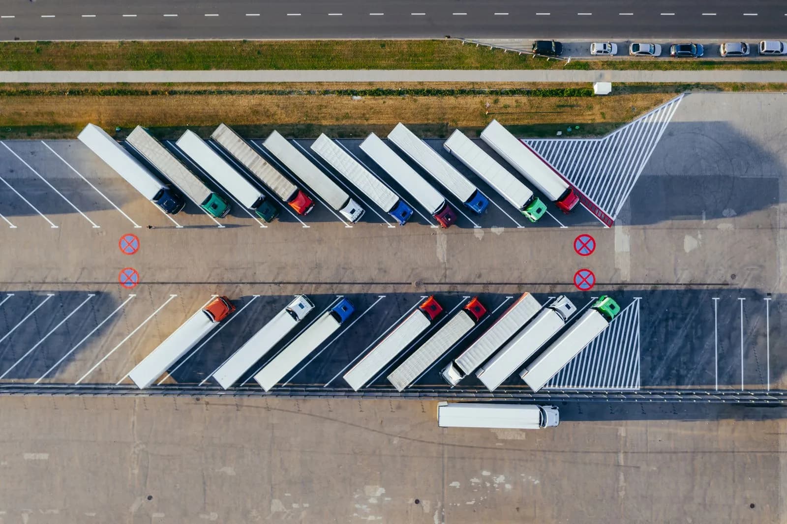 An aerial view of semi trucks parked in rows at a logistics yard