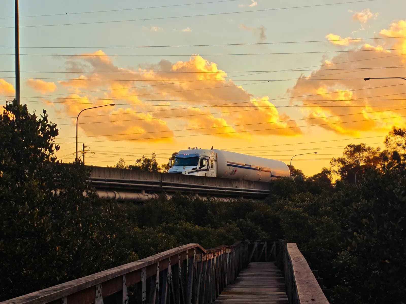 Tanker truck crossing a highway bridge at sunset