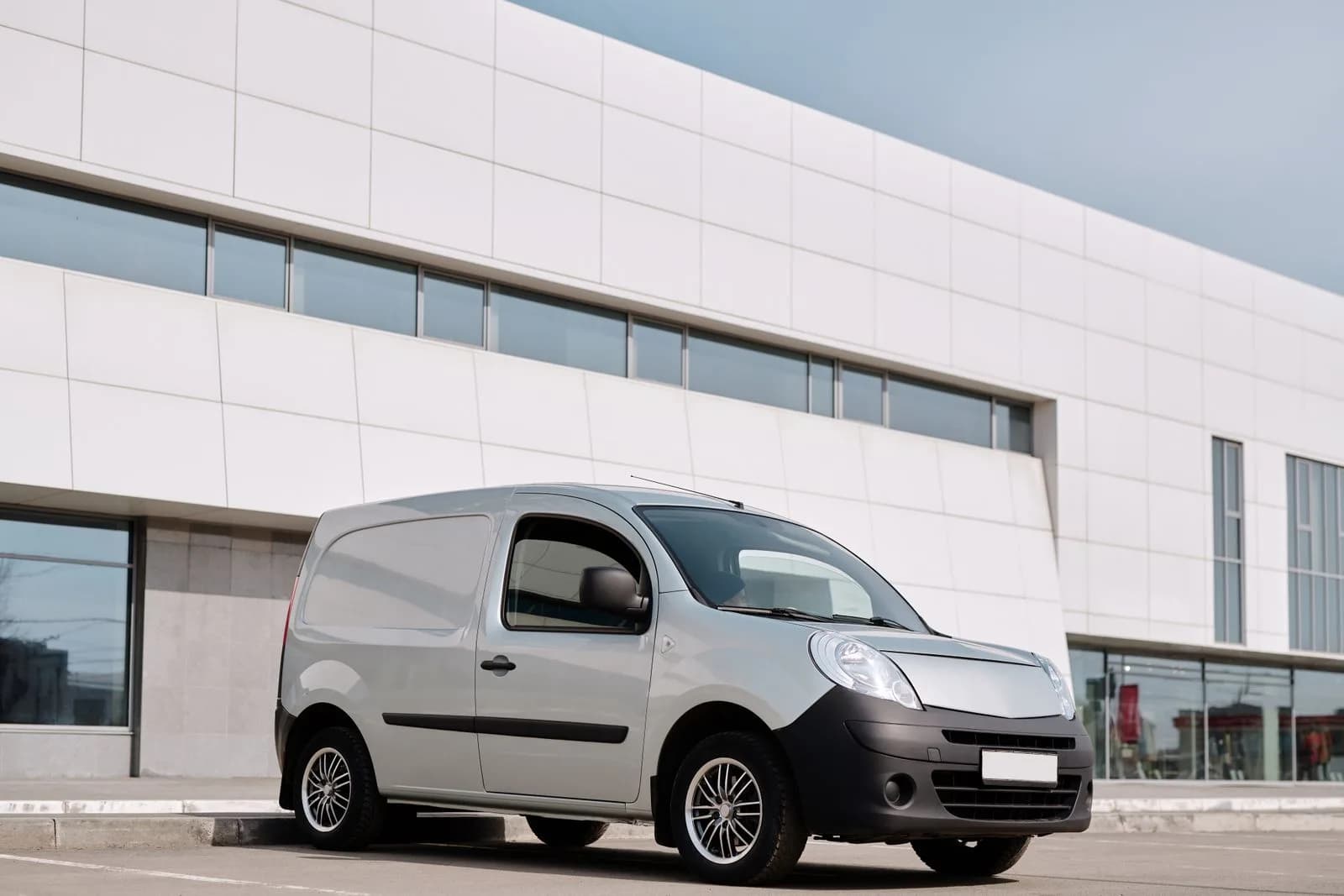A small fleet of white work vans parked outside a business