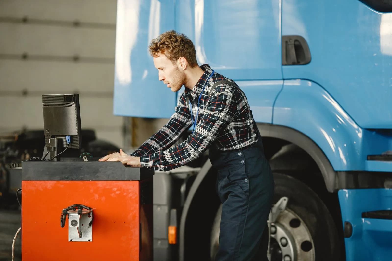 A technician using a diagnostic computer connected to a commercial truck