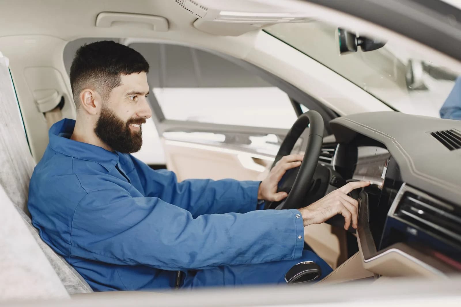 A technician reaching under a vehicle's dashboard near the steering column